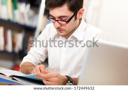Guy reading a book in a library