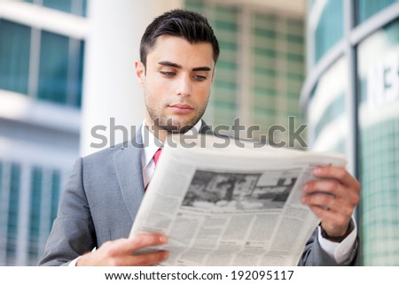 Portrait of a young business man reading a newspaper