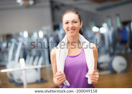 Portrait of a sporty young woman with towel in a gym