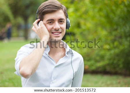 Smiling guy hearing music outdoors