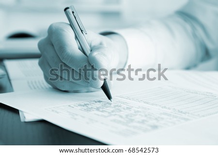 Blue toned image of a businessman writing a document in his office, useful for brochures