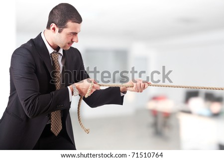Businessman pulling a rope in an office environment
