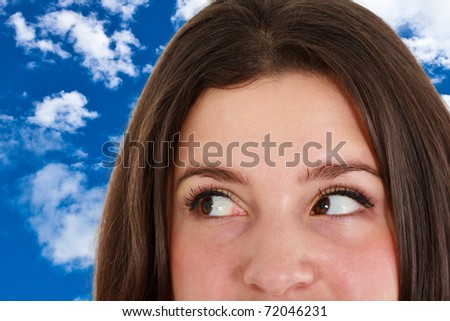 Young woman eyes close-up. Blue cloudy sky in the background.
