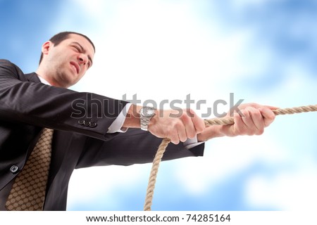 Angry businessman pulling a rope. Blue sky with clouds in the background.