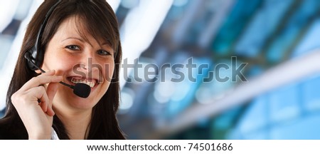 Young secretary smiling while helping a customer. Blue blurred background.