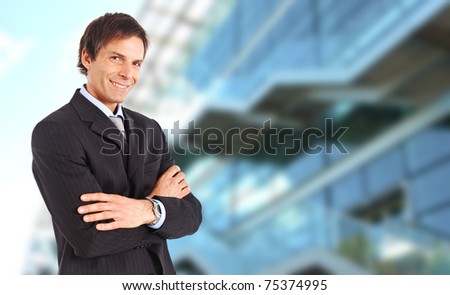 Mature businessman smiling against a blurred high tech glass building