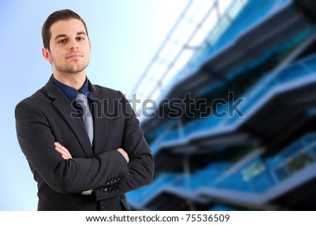 Confident young businessman against a blue high tech glass building