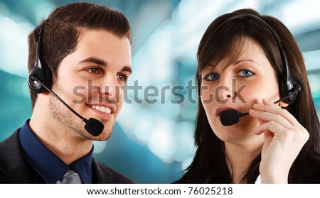Friendly phone operators helping a customer. Blue blurred background.