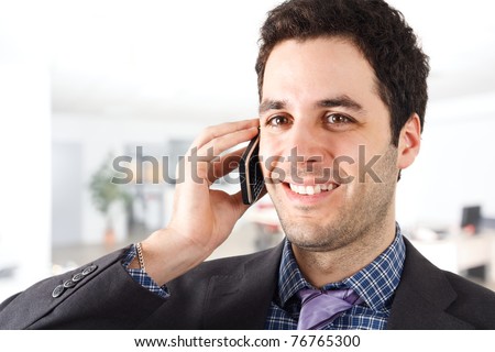 Young smiling businessman talking at phone in an office environment.