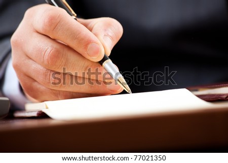 Closeup of a businessman\'s hands while writing some documents