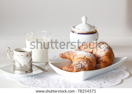 Continental breakfast with coffee, milk and croissants served on a table
