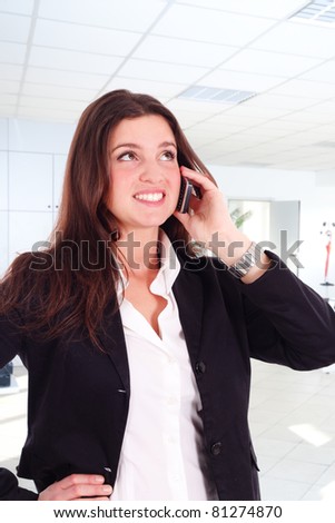 Young girl talking at the cellphone. Office background.