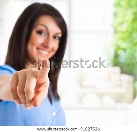 Portrait of a young smiling businesswoman pointing at you