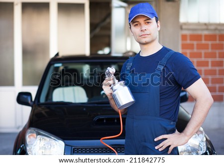 Car body repairer holding a spray gun