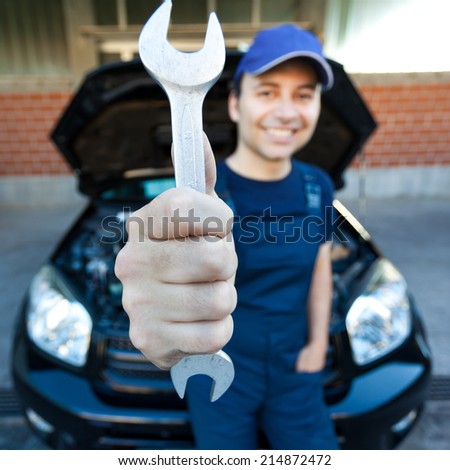 Smiling mechanic holding a wrench at a car garage