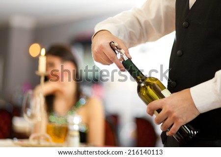 Waiter uncorking a wine bottle in a restaurant