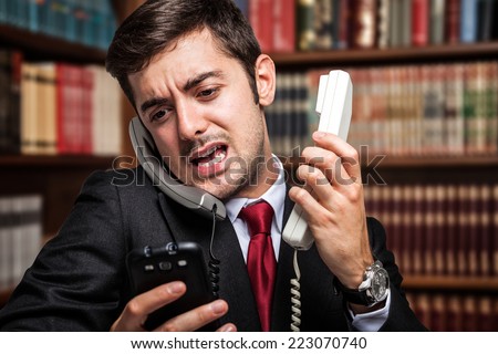 Stressed businessman talking on many phones at once