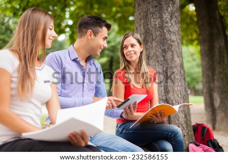 Outdoor portrait of three smiling students studying in a park