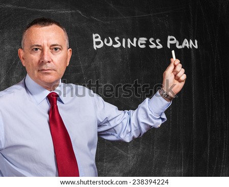Portrait of a businessman writing Business Plan on a blackboard