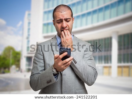 Portrait of a scared man looking at his mobile phone