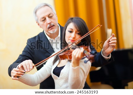Woman playing the violin with a teacher