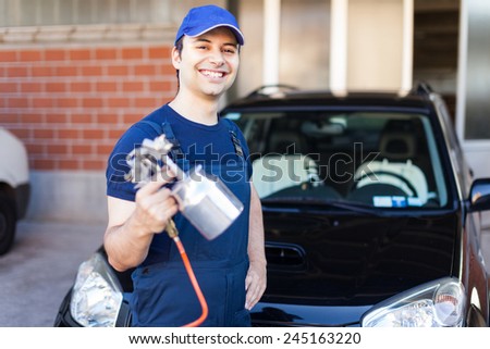 Car body repairer holding a spray gun