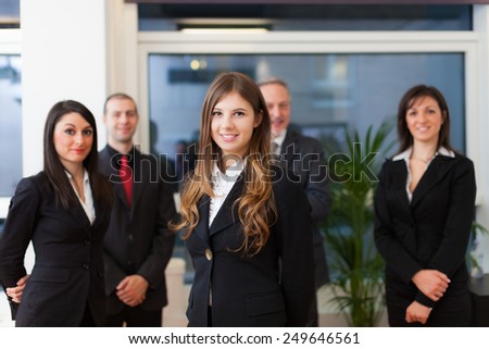Young smiling business woman in front of a group of business people