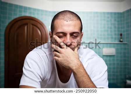 Portrait of a tired man looking in the mirror in his bathroom