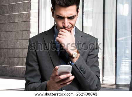 Puzzled man using his mobile phone