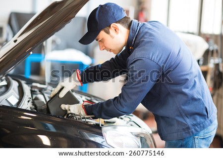Portrait of an auto mechanic putting oil in a car engine