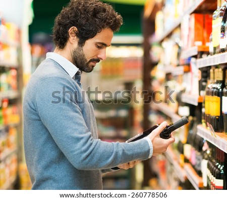 Man in a supermarket choosing a wine