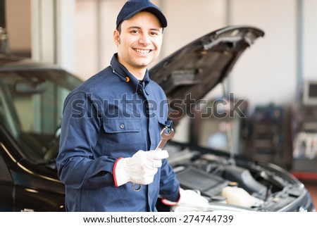 Portrait of a smiling mechanic holding a wrench in his garage