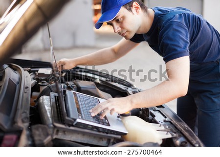 Skilled mechanic using a laptop computer to check a car engine