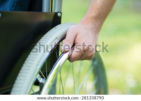 Detail of a man using a wheelchair in a park