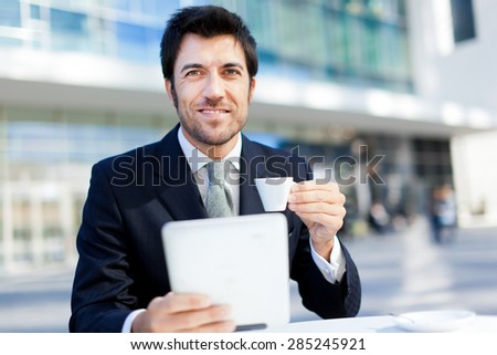 Businessman having breakfast and reading his tablet
