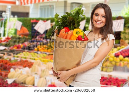 Woman holding a bag in a fruit and vegetable outdoor market