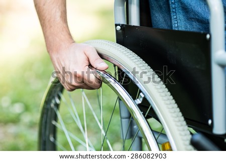 Close-up of male hand on the wheel of a wheelchair