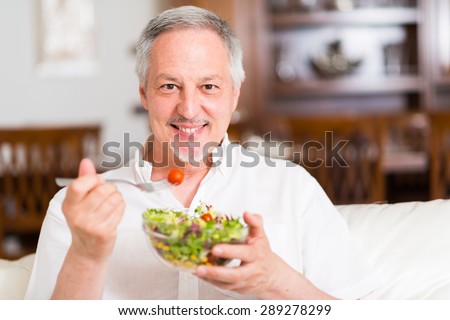 Portrait of a man eating a salad in his apartment