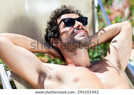 Young Man Sunbathing By Pool