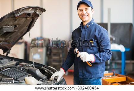 Mechanic holding a wrench while fixing a car in his shop