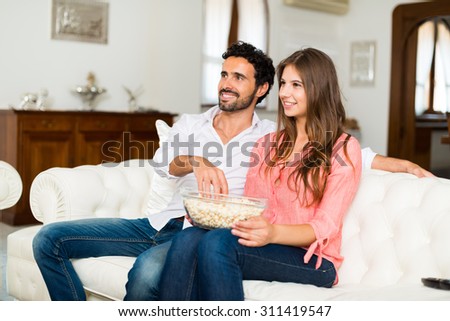 Happy smiling couple watching tv. Shallow depth of field, focus on the woman