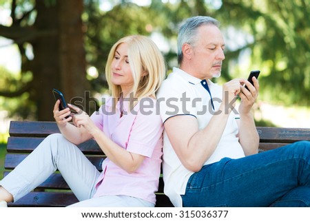 Mobile phone addiction concept - couple looking at their mobile phone while on a date