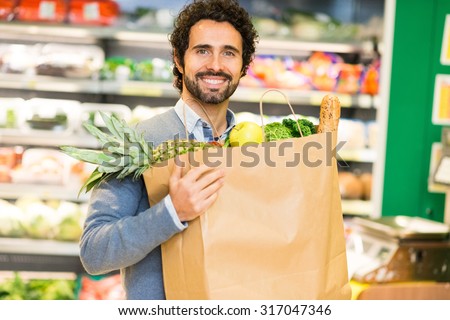 Smiling man holding a shopping bag in a supermarket
