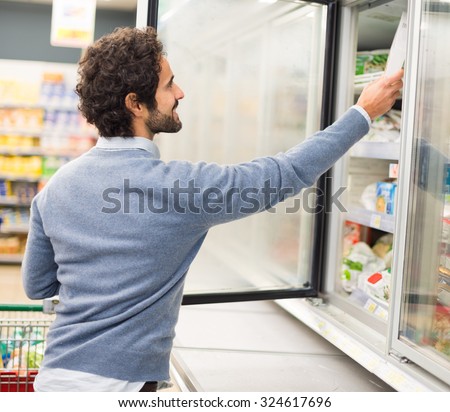 Man taking deep frozen food from a freezer in a supermarket