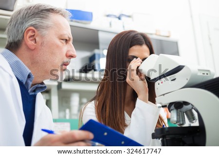 Two scientists discussing a medical document in their laboratory