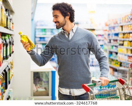 Man taking a bottle of oil from a shelf in a supermarket
