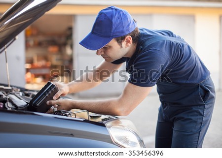 Portrait of an auto mechanic putting oil in a car engine