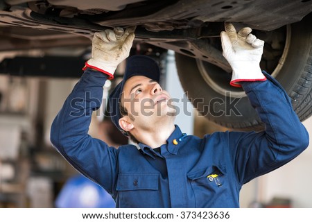 Portrait of a mechanic checking the condition a lifted car