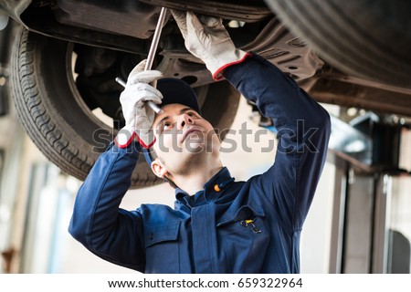 Portrait of a mechanic repairing a lifted car