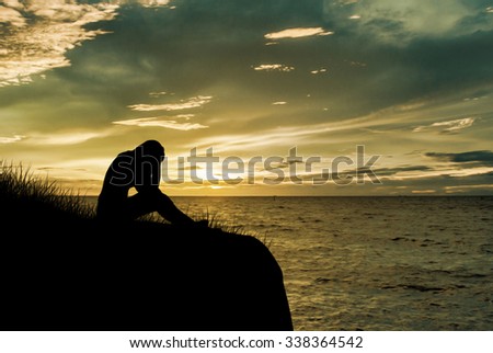 Woman sitting alone and sad depressed with meadow, Silhouette sunset.